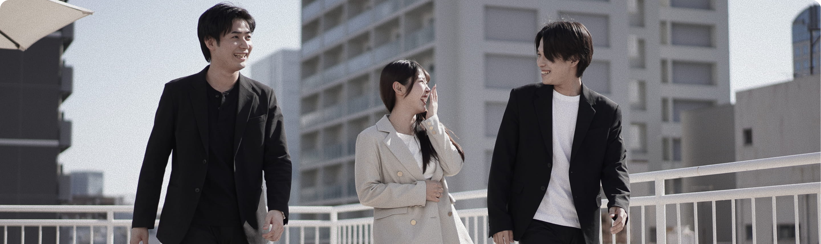 ビル街を歩きながら語り合う3人の社員