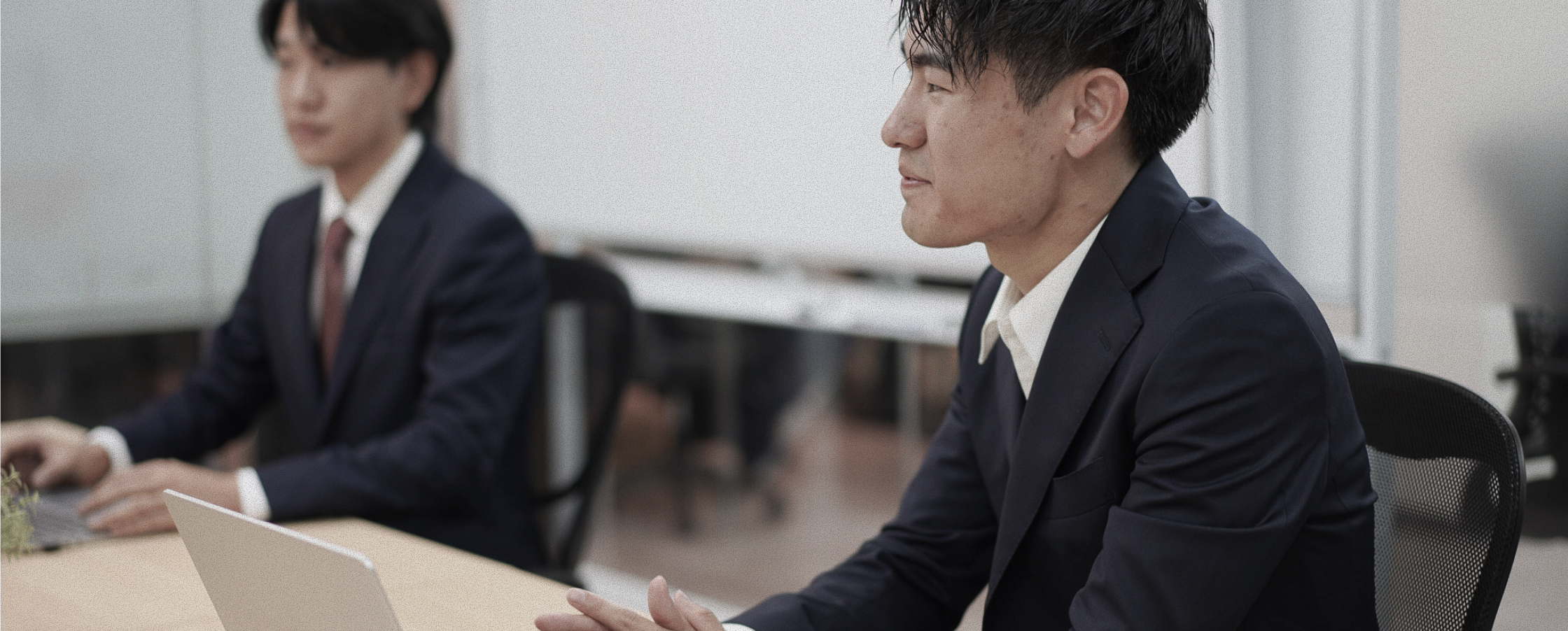 会議室でノートパソコンを開いて商談する2人の社員